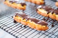 close-up of eclairs with shiny chocolate glaze on a cooling rack