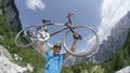 CLOSE UP: Ecstatic young cyclist lifts his road bicycle in beautiful mountains. Royalty Free Stock Photo