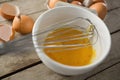 Close up of egg in bowl with wire whisk by eggshells Royalty Free Stock Photo