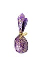 Close-up egg or ellipse shaped candy wrapped in puprle and golden paper with bow.