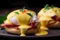 Close-up of eggs Benedict on a dark plate. Poached eggs on a bun and crispy bacon with a creamy hollandaise sauce. Food background