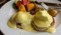 Close up of eggs benedict with two eggs and bacon on muffins with hollandaise sauce and pineapples Royalty Free Stock Photo