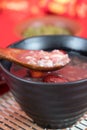 Close up eight treasure porridge scooped out of a bowl with a wooden spoon