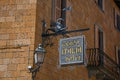 Close-up of elaborate Hotel plate, made of iron, stuck in stone wall and lamp in Orvieto.