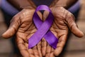 Close up of elderly black man\'s hands holding large purple Alzheimer disease awareness ribbon Royalty Free Stock Photo