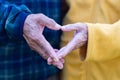Close-up of the elderly couple`s hand showing a heart-shaped symbol with fingers. Concept of aged people and love Royalty Free Stock Photo