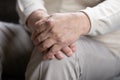 Close up elderly lonely man folded hands on lap