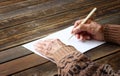 Close up of elderly male hands on wooden table . writing on blank paper Royalty Free Stock Photo