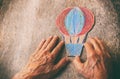 A close up of an elderly man holding a paper air balloon on a wooden table. Concept of thinking about childhood dreams, sadness an