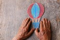 A close up of an elderly man holding a paper air baloon on a wooden table. Concept of thinking about childhood dreams, sadness and