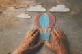 A close up of an elderly man holding a paper air baloon on a wooden table. Concept of thinking about childhood dreams, sadness and