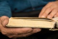 Close-up of an elderly man`s hands holding an old open book. The old man is reading a book. old yellowed book in the hands of a Royalty Free Stock Photo