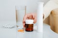 Close-up of elderly woman holding medicine bottle, pills, glass of water on table indoors. Royalty Free Stock Photo