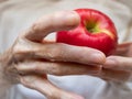 Close Up of Elderly Woman`s Hands Holding a Red Apple