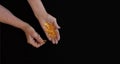 In the hands of an elderly woman, yellow pills. Close-up on a black background