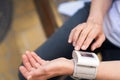 Close-up of elderly woman's hands holding pressure measurement device outdoors. The image portrays the concept of