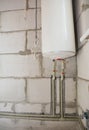A close-up of an electric hot water heater, boiler pipes connection in the bottom and the water heater installation by hanging it Royalty Free Stock Photo