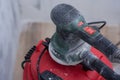 Close-up of electric sander connected to a dust extractor vacuum during wall sanding work. Concept construction tools covered in Royalty Free Stock Photo