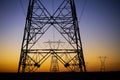 Close up of electrical transmission tower with another tower in distance against desert sunset sky Royalty Free Stock Photo