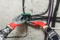 Close up of electrician' hands in working gloves mounting electrical junction box with wires Royalty Free Stock Photo