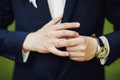 close-up of elegance male hands. man dressed in blue suit and white shirt standing over green nature background. groom or