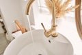 Close-up of an elegant golden faucet in the bathroom sink next to stylish decorations. A beautiful sink with a golden Royalty Free Stock Photo