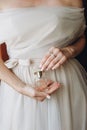 Close up of elegant perfume in a glass bottle in the hands of the bride in a wedding dress. Royalty Free Stock Photo