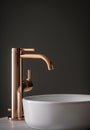 Close-up of an elegant rose golden faucet in the bathroom sink next to stylish decorations. A beautiful sink with a Royalty Free Stock Photo