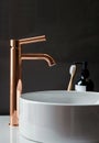 Close-up of an elegant rose golden faucet in the bathroom sink next to stylish decorations. A beautiful sink with a Royalty Free Stock Photo