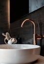 Close-up of an elegant rose golden faucet in the bathroom sink next to stylish decorations. A beautiful sink with a Royalty Free Stock Photo