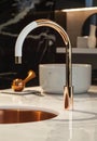 Close-up of an elegant rose golden faucet in the bathroom sink next to stylish decorations. A beautiful sink with a Royalty Free Stock Photo