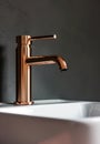 Close-up of an elegant rose golden faucet in the bathroom sink next to stylish decorations. A beautiful sink with a Royalty Free Stock Photo