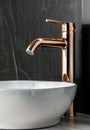 Close-up of an elegant rose golden faucet in the bathroom sink next to stylish decorations. A beautiful sink with a Royalty Free Stock Photo