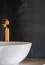 Close-up of an elegant rose golden faucet in the bathroom sink next to stylish decorations. A beautiful sink with a Royalty Free Stock Photo