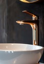 Close-up of an elegant rose golden faucet in the bathroom sink next to stylish decorations. A beautiful sink with a Royalty Free Stock Photo