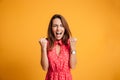 Close-up of emotional brunette woman keeping hands in fists, screaming while celebrating win