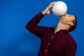 Close up of emotional caucasian man playing soccer hitting the ball with his mouth on isolated blue background. Soccer Royalty Free Stock Photo
