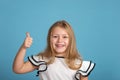 Close up emotional porClose up emotional portrait of young blonde smiling girl wearing white blous with black strips on blue Royalty Free Stock Photo