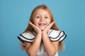 Close up emotional portrait of young blonde smiling girl wearing white blous with black strips on blue background in studio. She Royalty Free Stock Photo