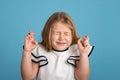 Close up emotional portrait of young blonde smiling girl wearing white blous with black strips on blue background in studio. She Royalty Free Stock Photo