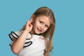 Close up emotional portrait of young blonde smiling girl on blue background in studio. She Royalty Free Stock Photo