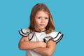 Close up emotional portrait of young blonde girl wearing white blous with black strips on blue background in studio. She Royalty Free Stock Photo