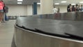 CLOSE UP: Empty baggage carousel spins while passengers wait patiently for bags.