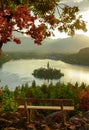 CLOSE UP: Empty bench overlooks the calm Lake Bled and islet in morning sunshine Royalty Free Stock Photo