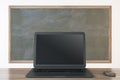 Close up of empty black laptop and mouse on chalkboard background, Education, seminar, workshop and mockup concept.