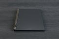 Close up of empty black spiral notepad on dark wooden background. Mock up Royalty Free Stock Photo