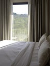 Close up empty clean bed with two pillows near the glass door and curtain.