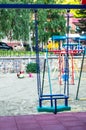 Close-up of empty colorful plastic baby swing on Playground in Park on summer day Royalty Free Stock Photo