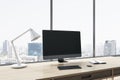 Close up of empty computer display on wooden office desktop with objects, lamp and supplies on panoramic window and city view Royalty Free Stock Photo