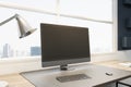 Close up of empty computer screen on wooden office desk with objects, lamp and supplies on panoramic window and city view Royalty Free Stock Photo